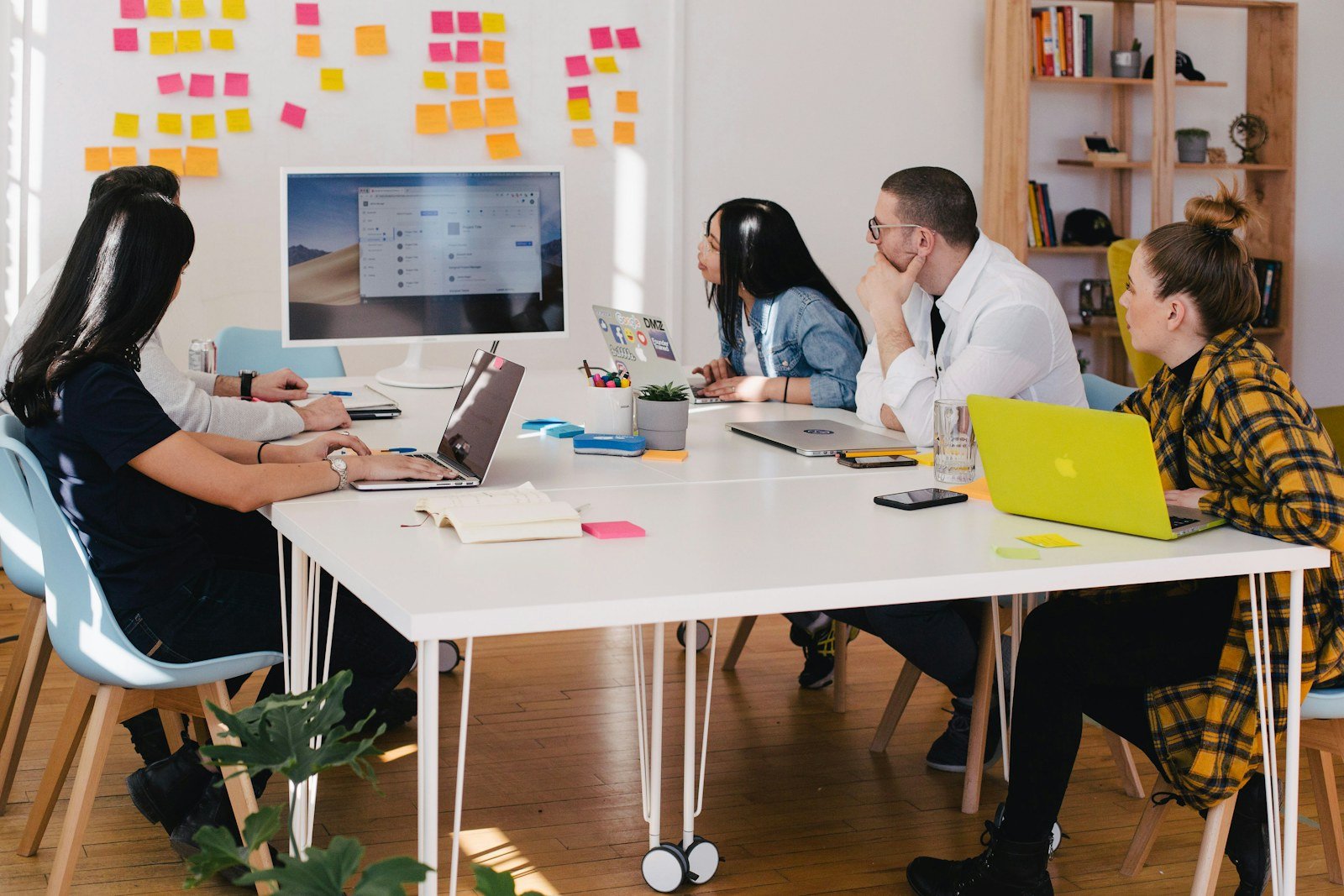 A team gathered around a table for a working session, sticky notes on the wall behind them