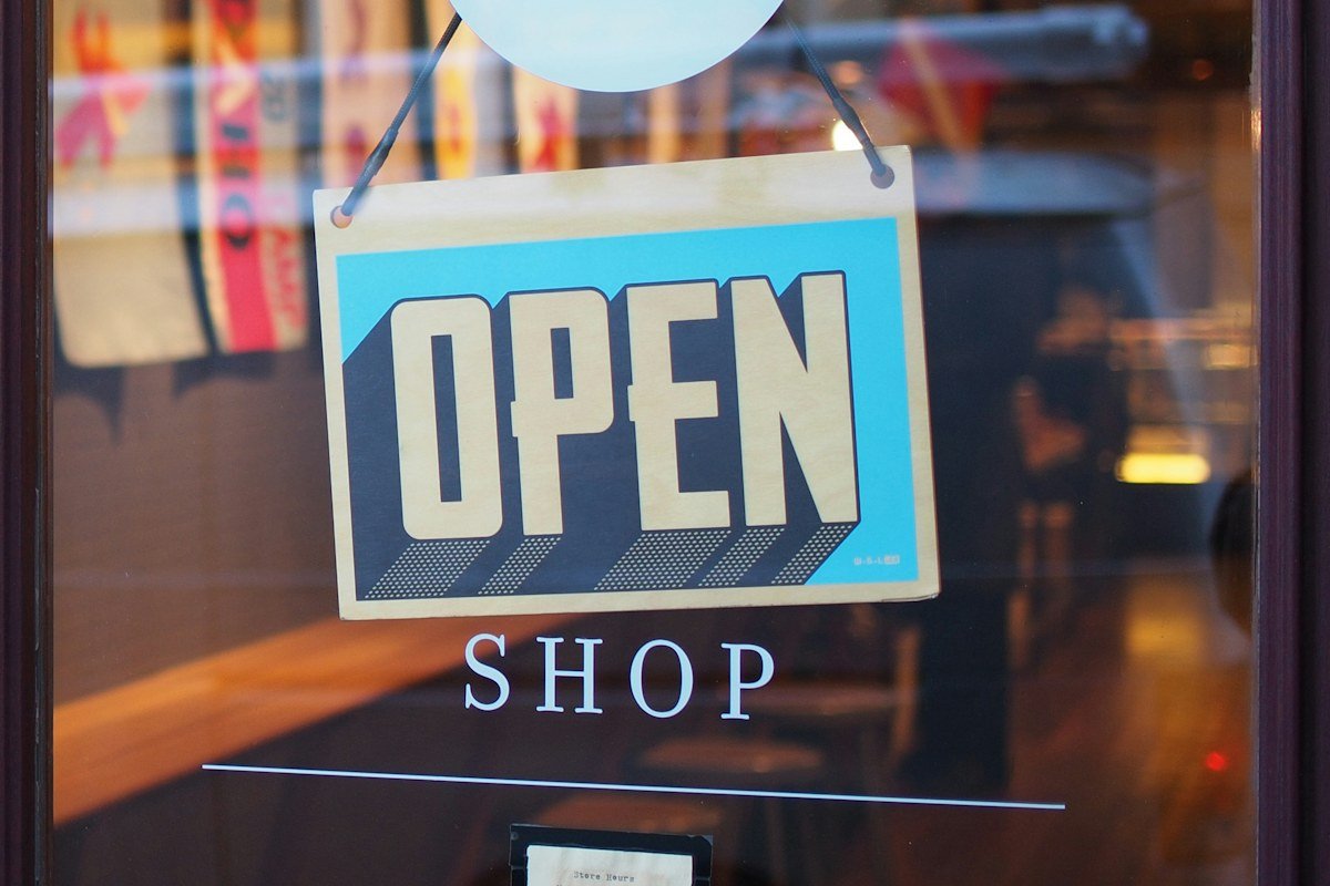 A neon 'Open Shop' sign lit up in a storefront window