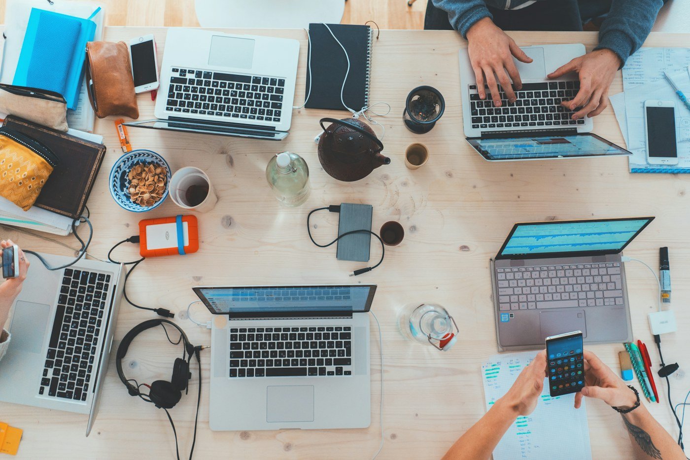 Overhead view of engineers' desk with laptops, notebooks, and coffee during a working session