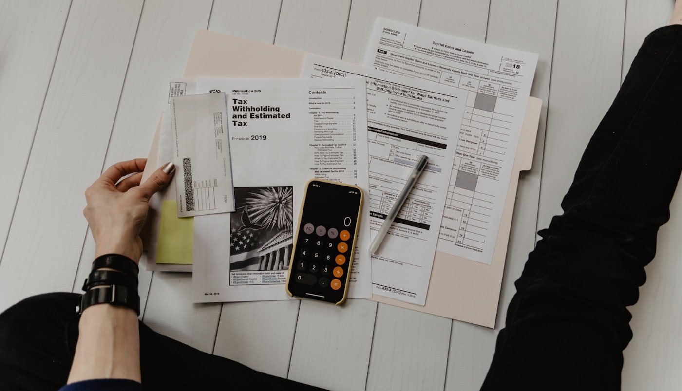 Hands reviewing tax documents and a calculator on a desk